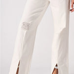 Lower body shot highlighting the straight leg cut, frayed distressed patches, and ankle splits.