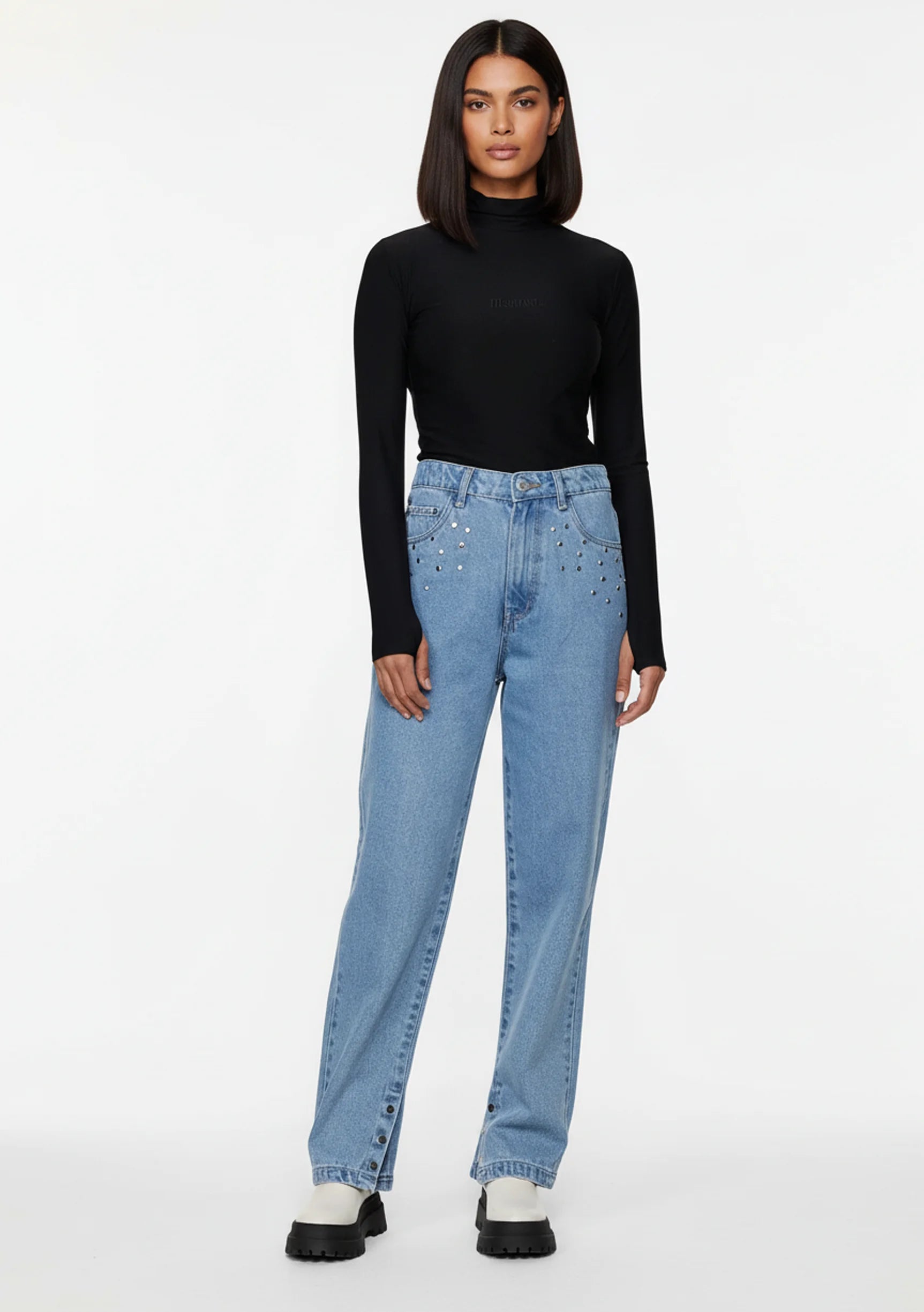 Model standing in a relaxed pose wearing female straight jeans with embellished front pockets.