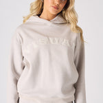 Close up front shot of a woman in a stone hoodie with a text graphic