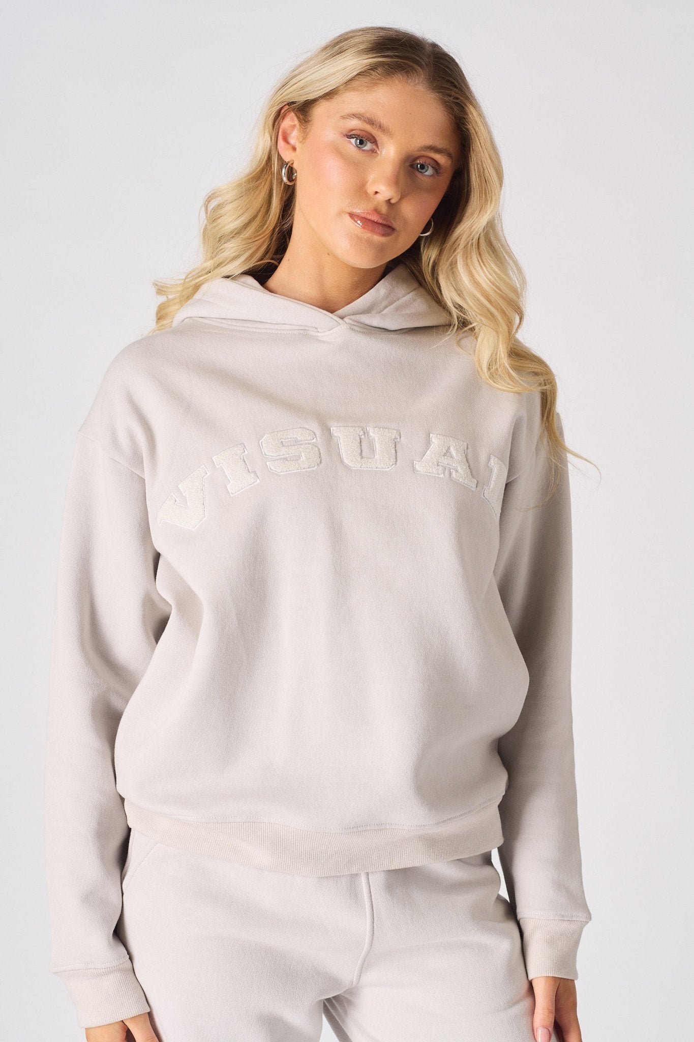 Close up front shot of a woman in a stone hoodie with a text graphic