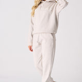 Side view of a woman walking in a matching stone hoodie and joggers set