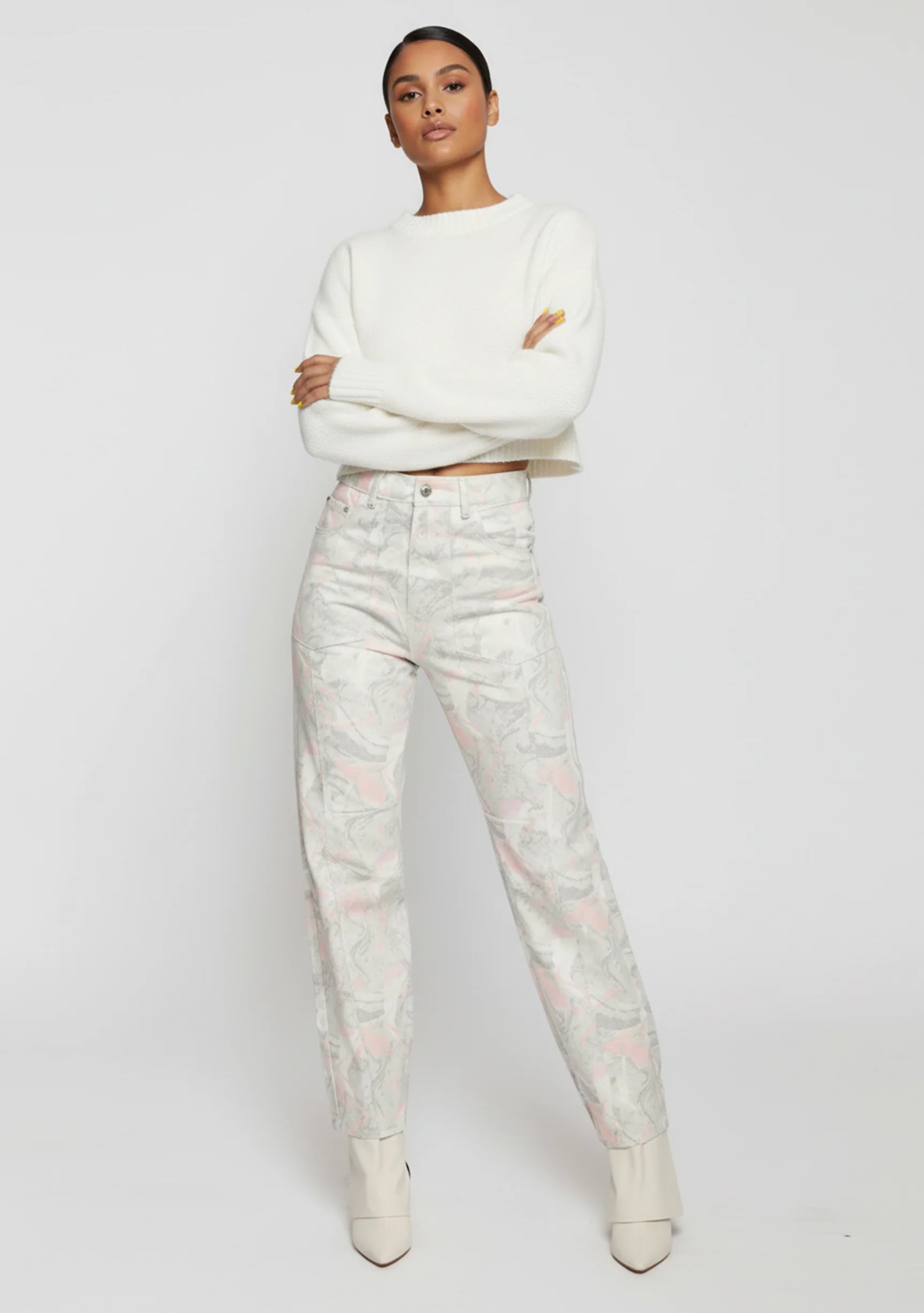 Model standing with arms crossed wearing female swirl wash tapered leg jeans in a light grey tone.