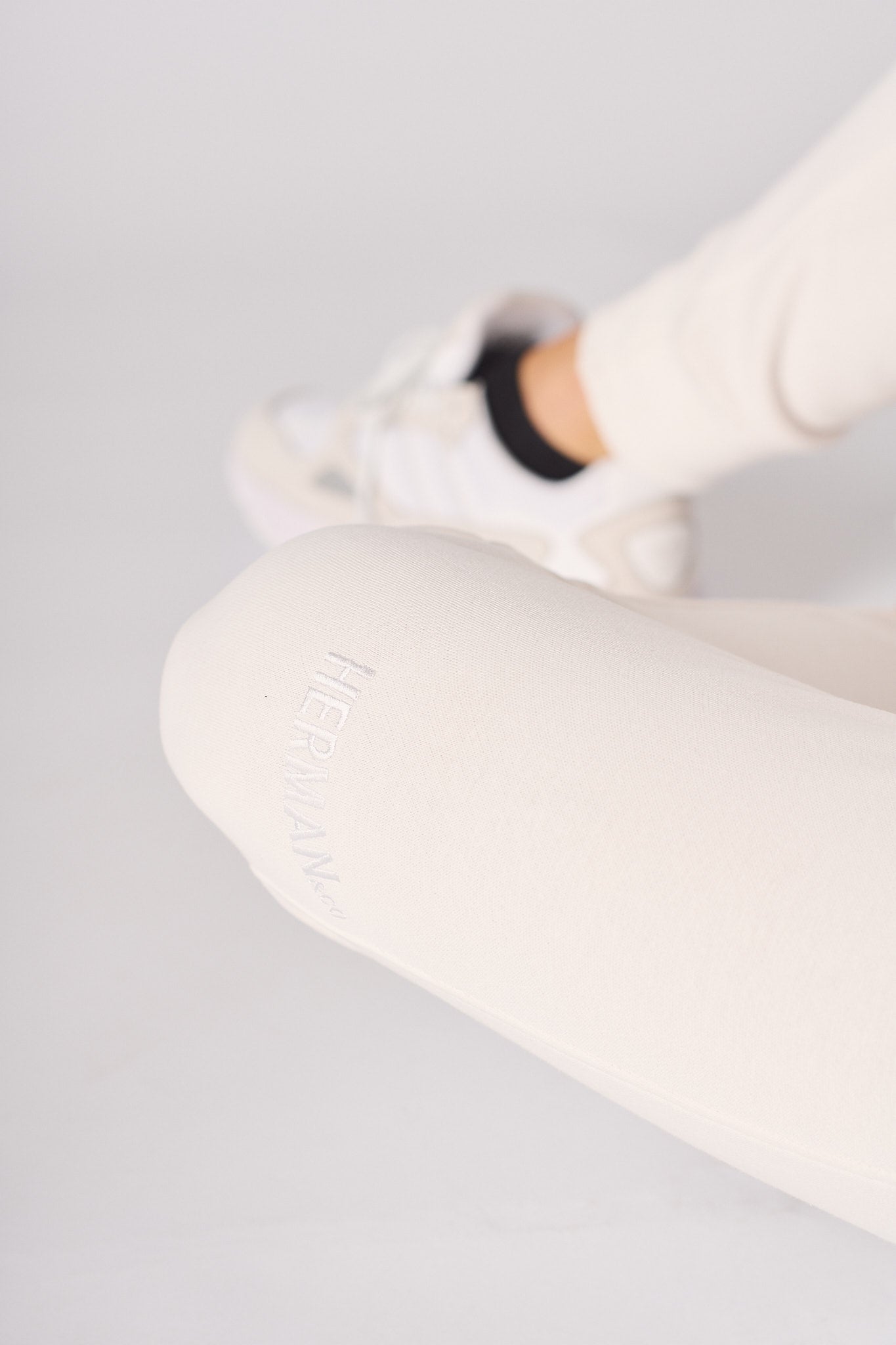Close up showing the soft texture and fit of the female white sweatpants.
