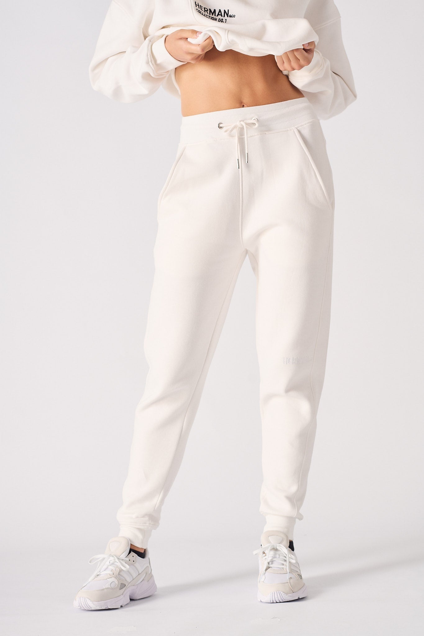 A woman wearing stylish female white sweatpants in a front view shot.