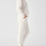 Side view of a woman posing in the relaxed fit female white sweatpants.