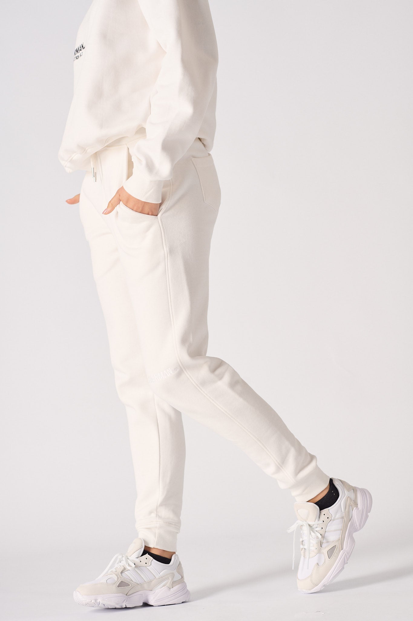 Side profile of a model walking in comfortable female white sweatpants.