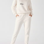 Front view of a model walking while wearing premium female white sweatpants.