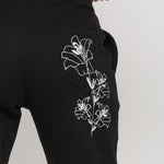 Close-up of the delicate white floral embroidery on the back pocket of the joggers