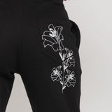 Close-up of the delicate white floral embroidery on the back pocket of the joggers