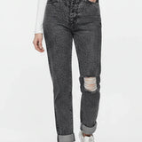 Person wearing gray distressed jeans and white sneakers on a white background