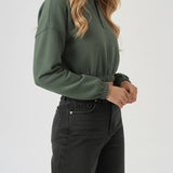 Side view of a model posing in a cropped green half zip sweatshirt