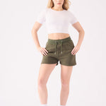 A front view of a woman wearing khaki green jogger shorts with a white crop top