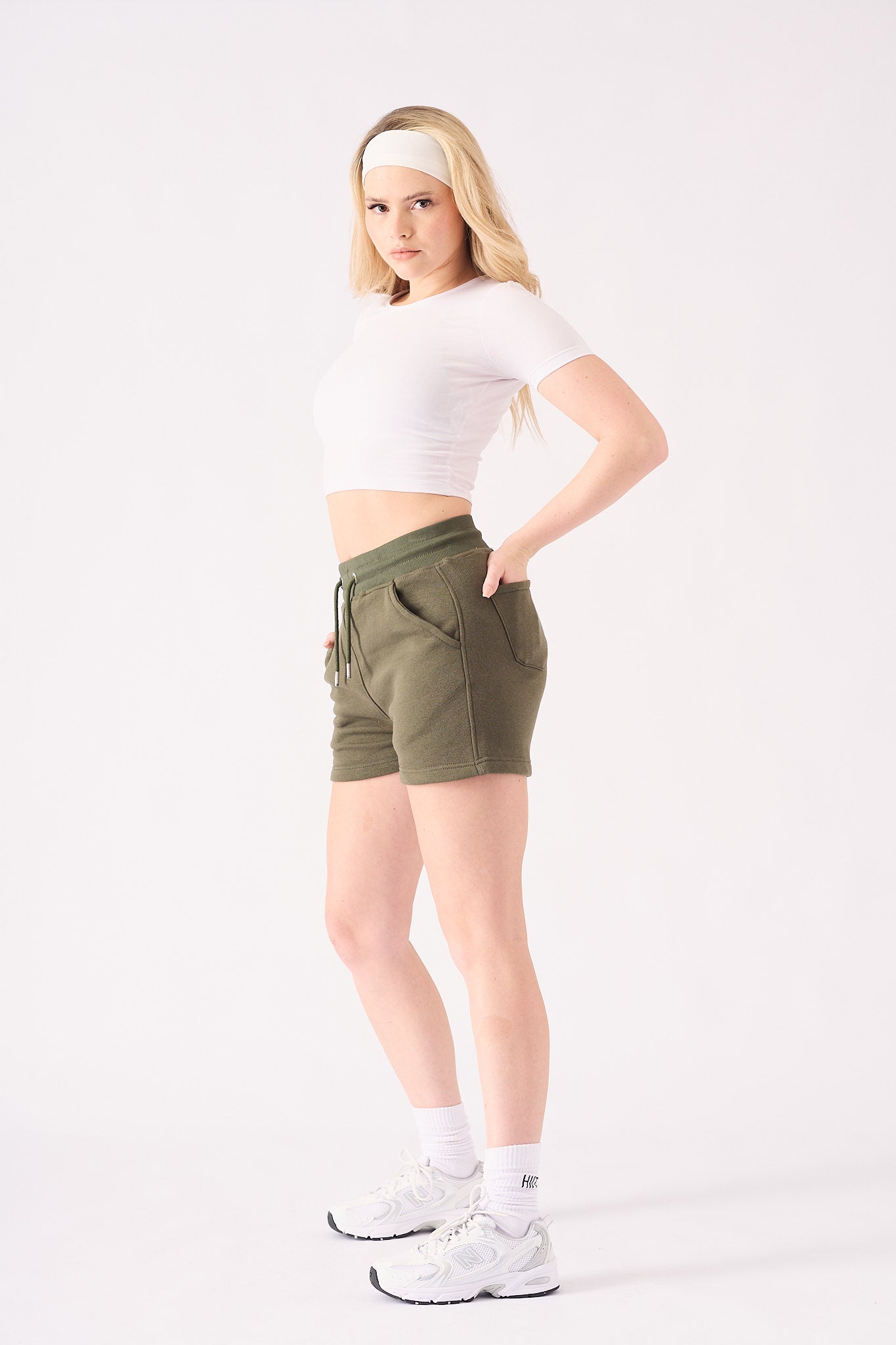 A woman wearing a white headband and green jogger shorts for a casual outfit