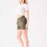 Side profile of a woman posing in comfortable green jogger shorts for a relaxed look
