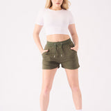 Full front view of a model styling green jogger shorts with white trainers