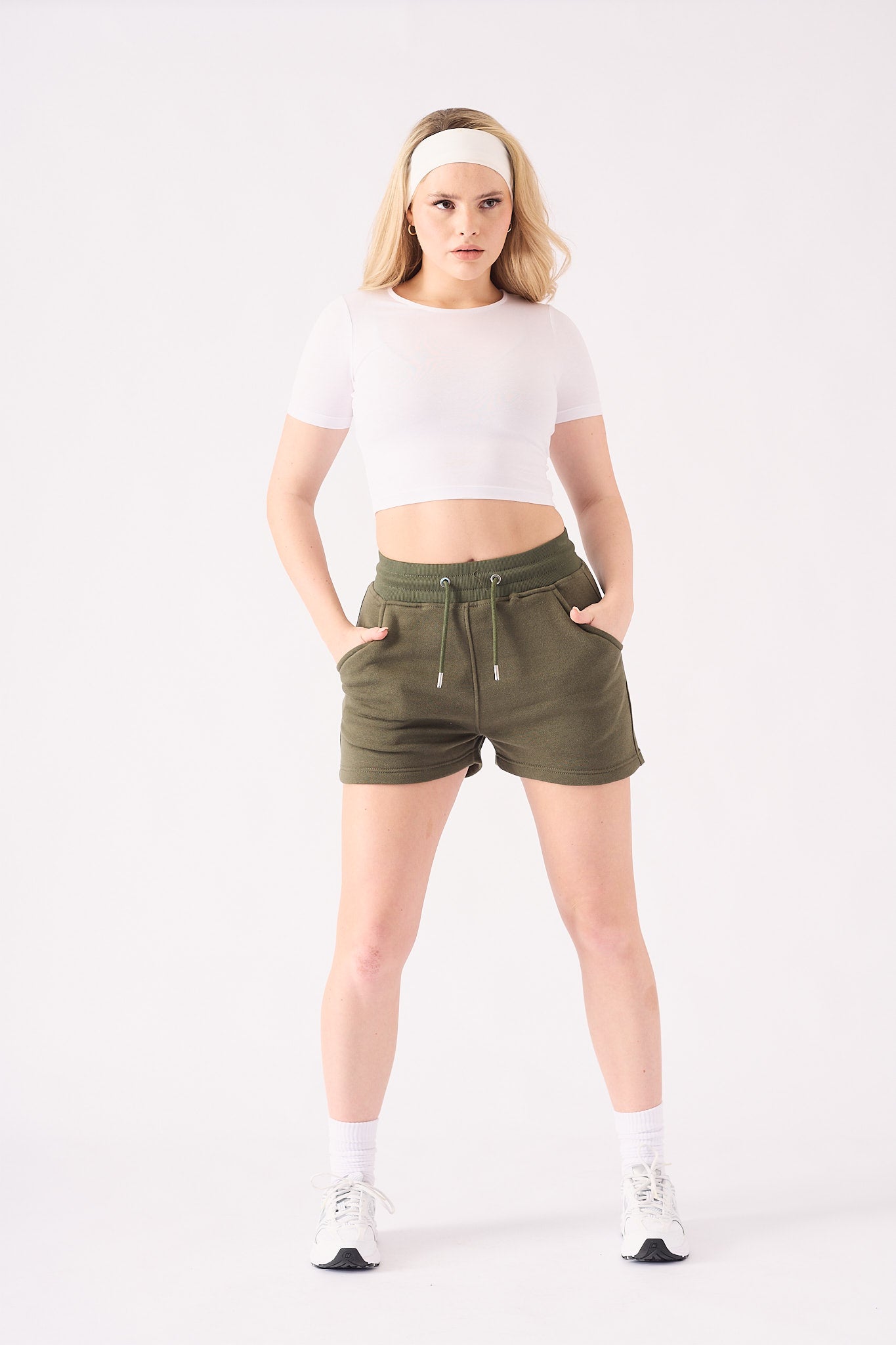 Full front view of a model styling green jogger shorts with white trainers