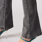 Close up of the wide bootcut hem and seam detail on charcoal grey denim jeans
