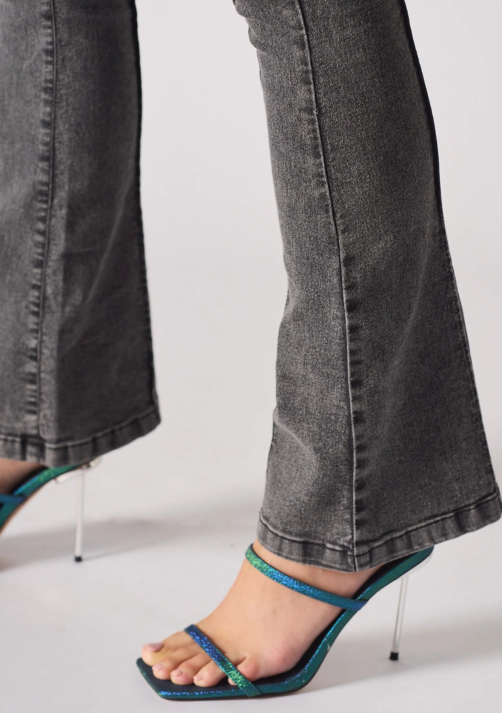 Close up of the wide bootcut hem and seam detail on charcoal grey denim jeans