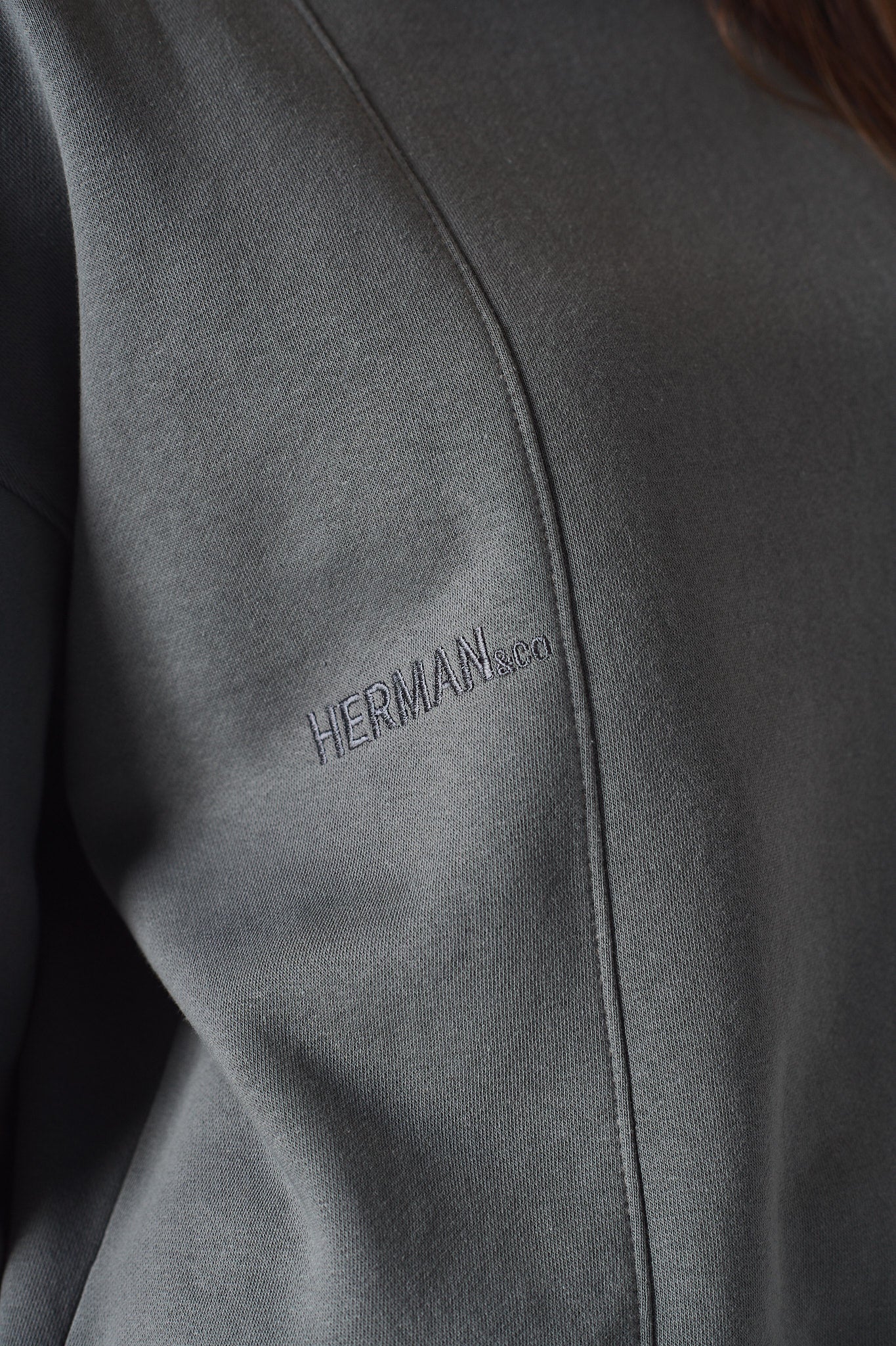 close up of embroidered logo on grey crew neck jumper