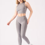 A model wearing a grey racer neck crop top with matching grey leggings