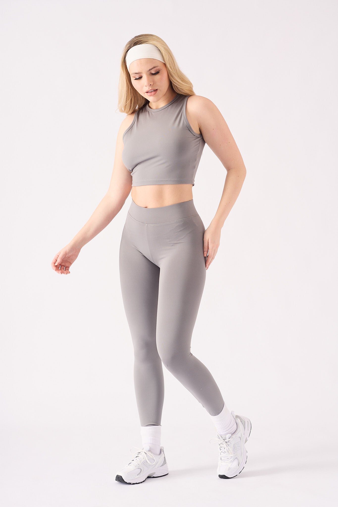 A model wearing a grey racer neck crop top with matching grey leggings