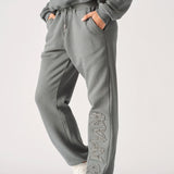 A model posing in premium grey cuffed joggers womens with white trainers.