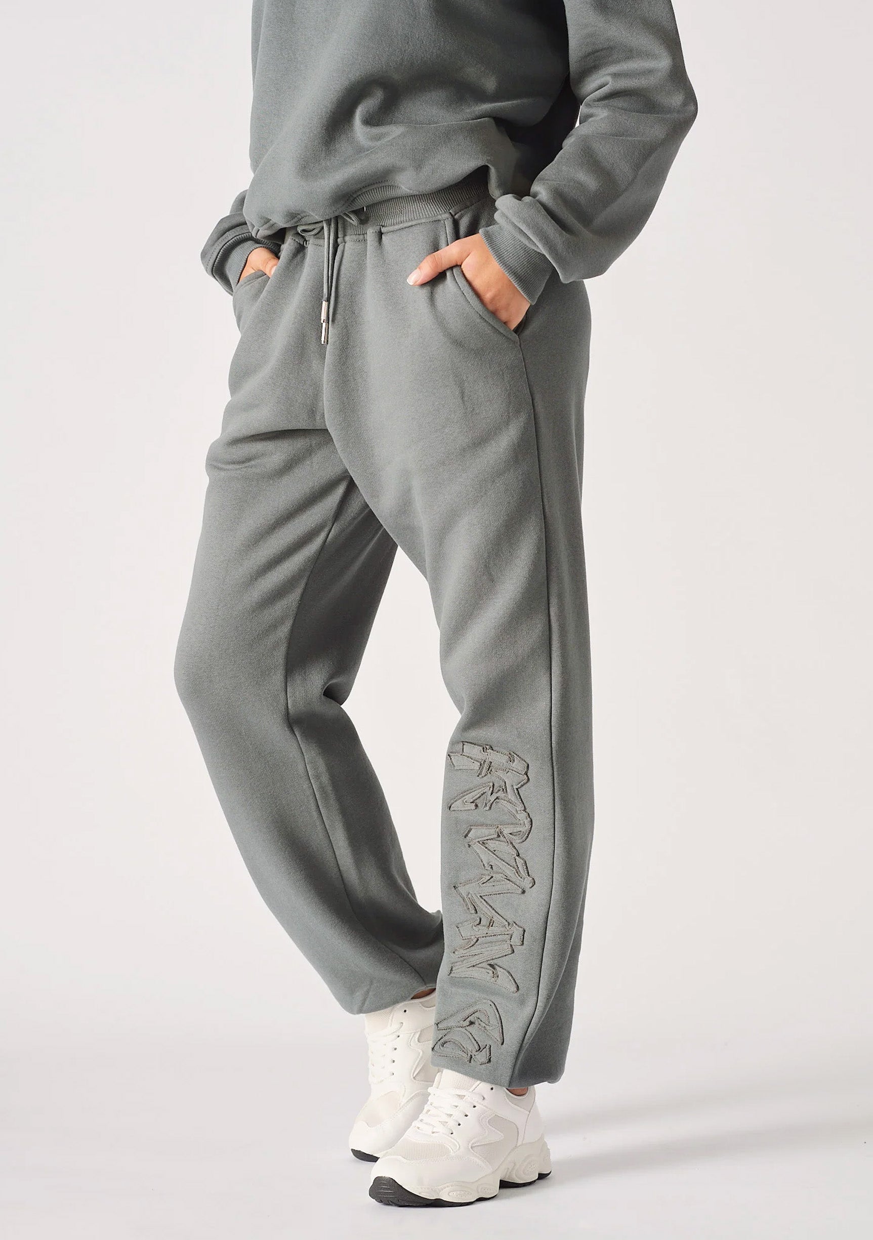 A model posing in premium grey cuffed joggers womens with white trainers.