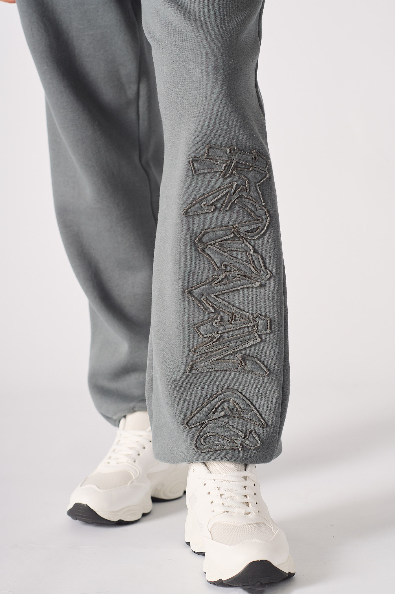 Close up of the architectural tonal embroidery on the grey cuffed joggers womens.