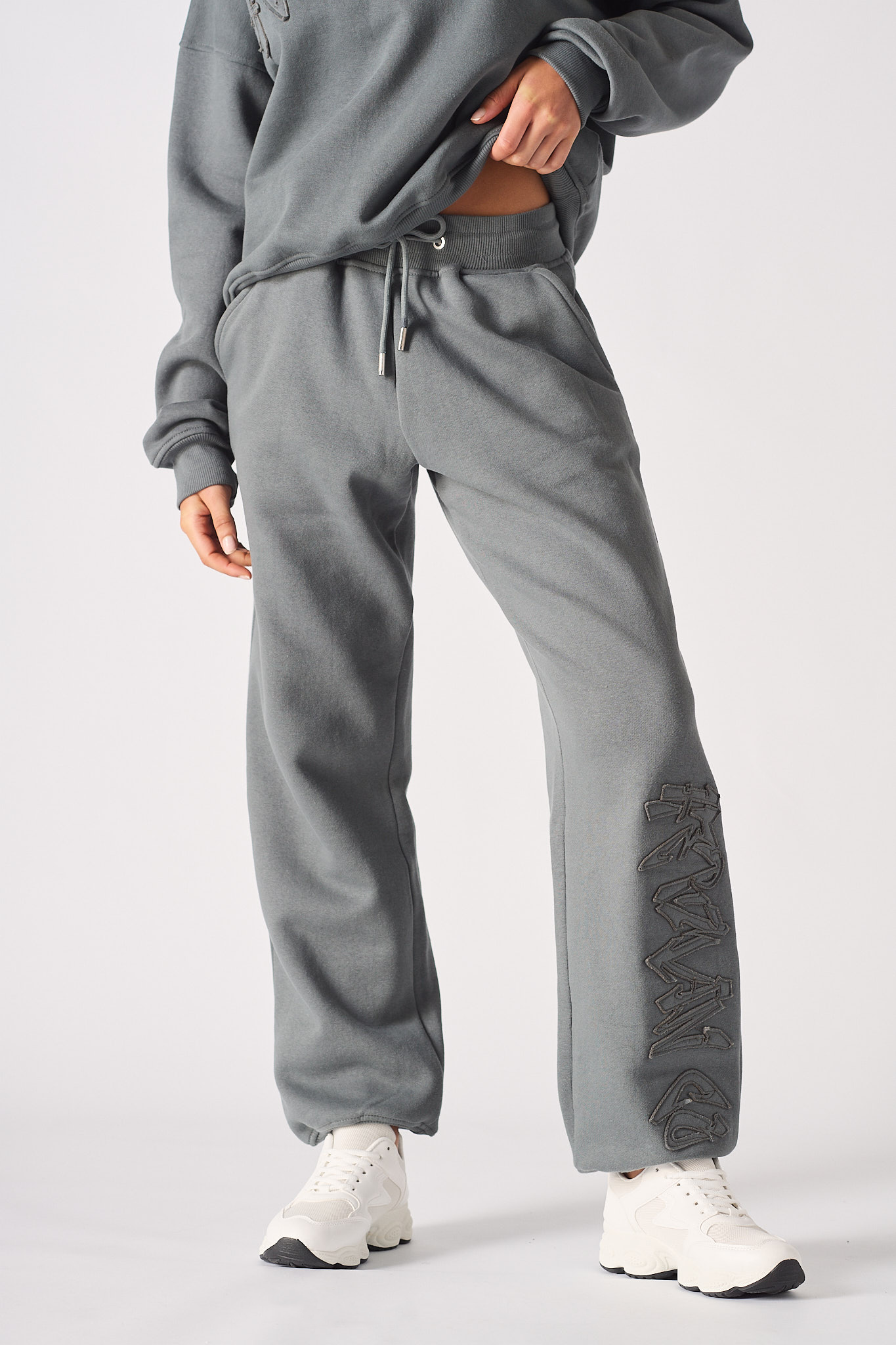 Full body shot of a woman in grey cuffed joggers womens and a matching top.