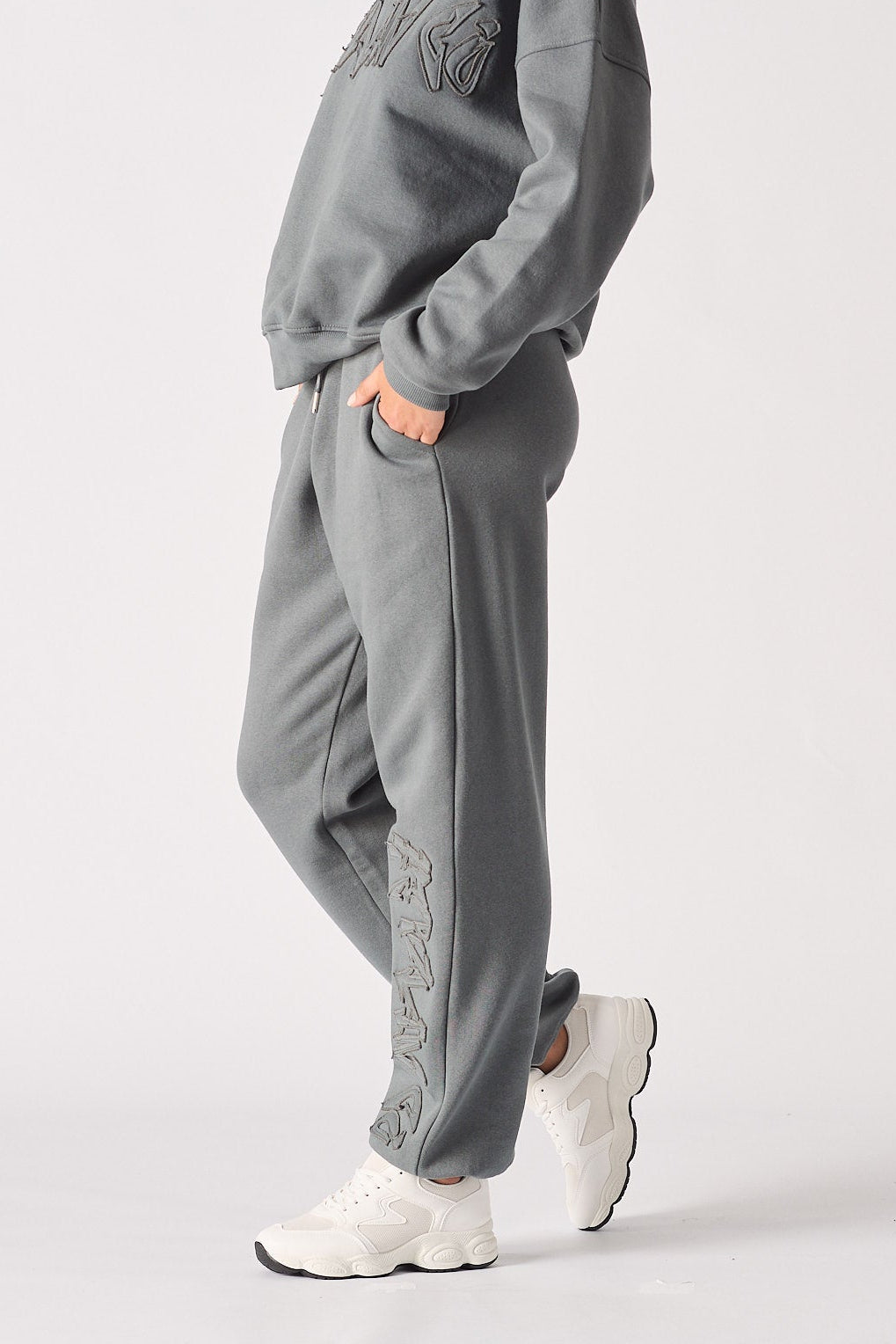 A woman wearing grey cuffed joggers womens in a relaxed side pose.