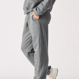 A woman wearing grey cuffed joggers womens in a relaxed side pose.