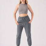 Full body shot of a woman in grey tapered joggers womens and a matching top.