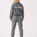 Rear view of a grey zip up hoodie for women showing a bold white puff print logo