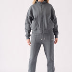 A woman posing in a grey zip up hoodie with hands in the side pockets