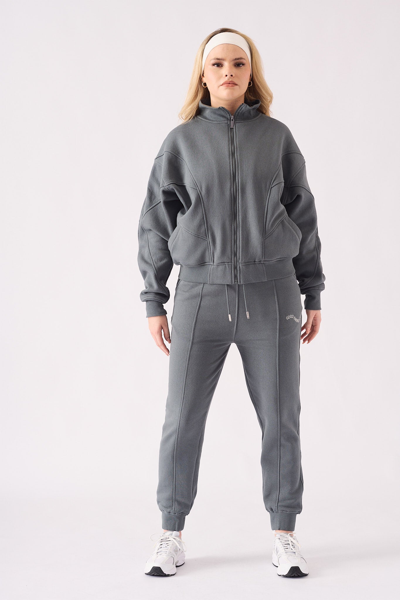 A woman posing in a grey zip up hoodie with hands in the side pockets