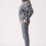 Full body side view of a model in a grey zip up hoodie and tracksuit set