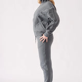 Full body side view of a model in a grey zip up hoodie and tracksuit set