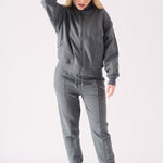 A model wearing a grey zip up hoodie with a white headband and matching joggers