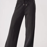 Model wearing Herman's black wide-leg joggers with a relaxed fit, showing the drawstring waist and pintuck seam detail.