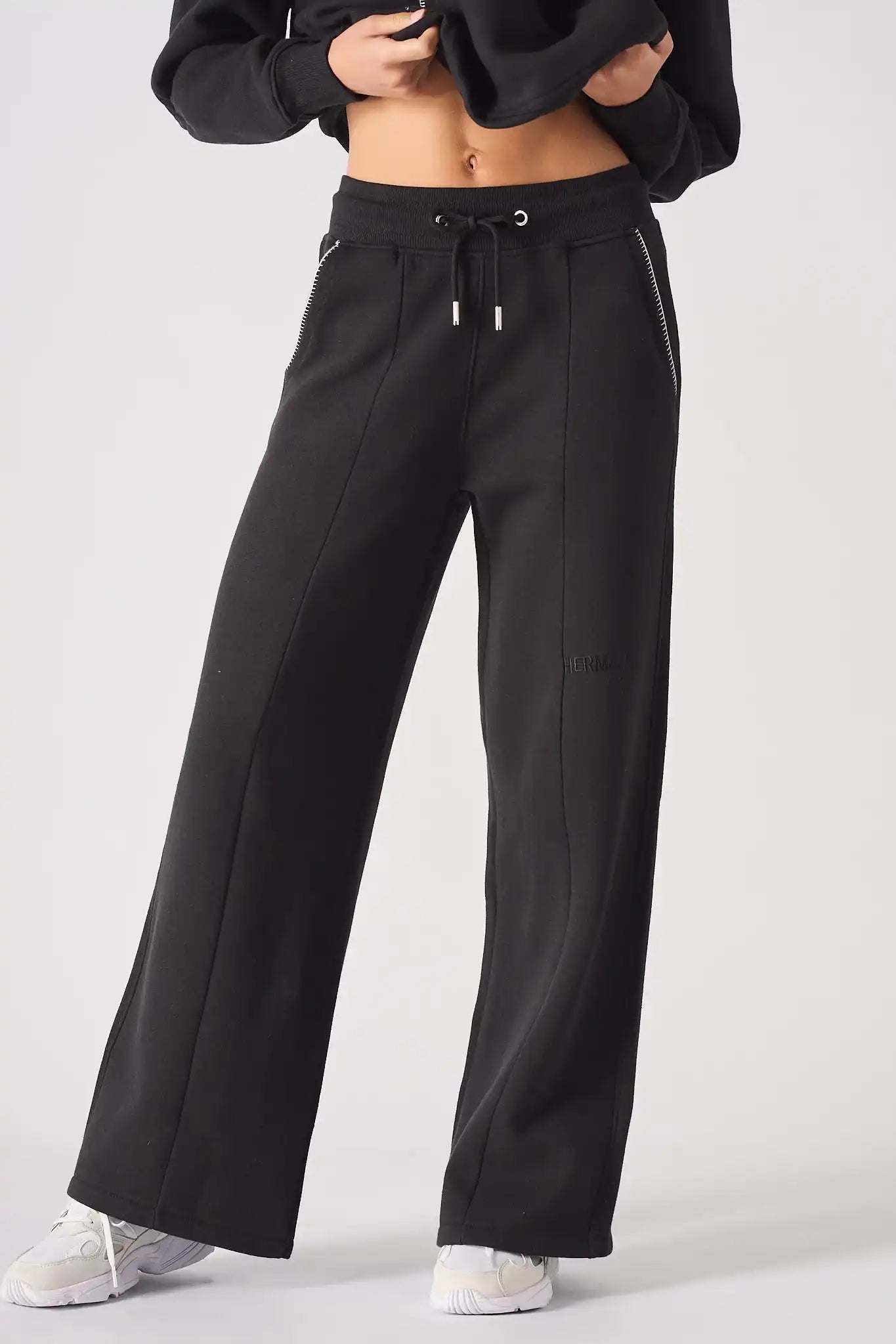 Model wearing Herman's black wide-leg joggers with a relaxed fit, showing the drawstring waist and pintuck seam detail.