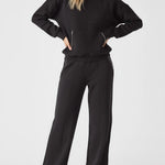 Model styled in a full loungewear set featuring the Herman black wide-leg joggers and a matching black sweatshirt