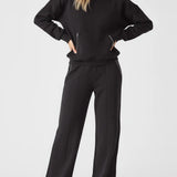 Model styled in a full loungewear set featuring the Herman black wide-leg joggers and a matching black sweatshirt