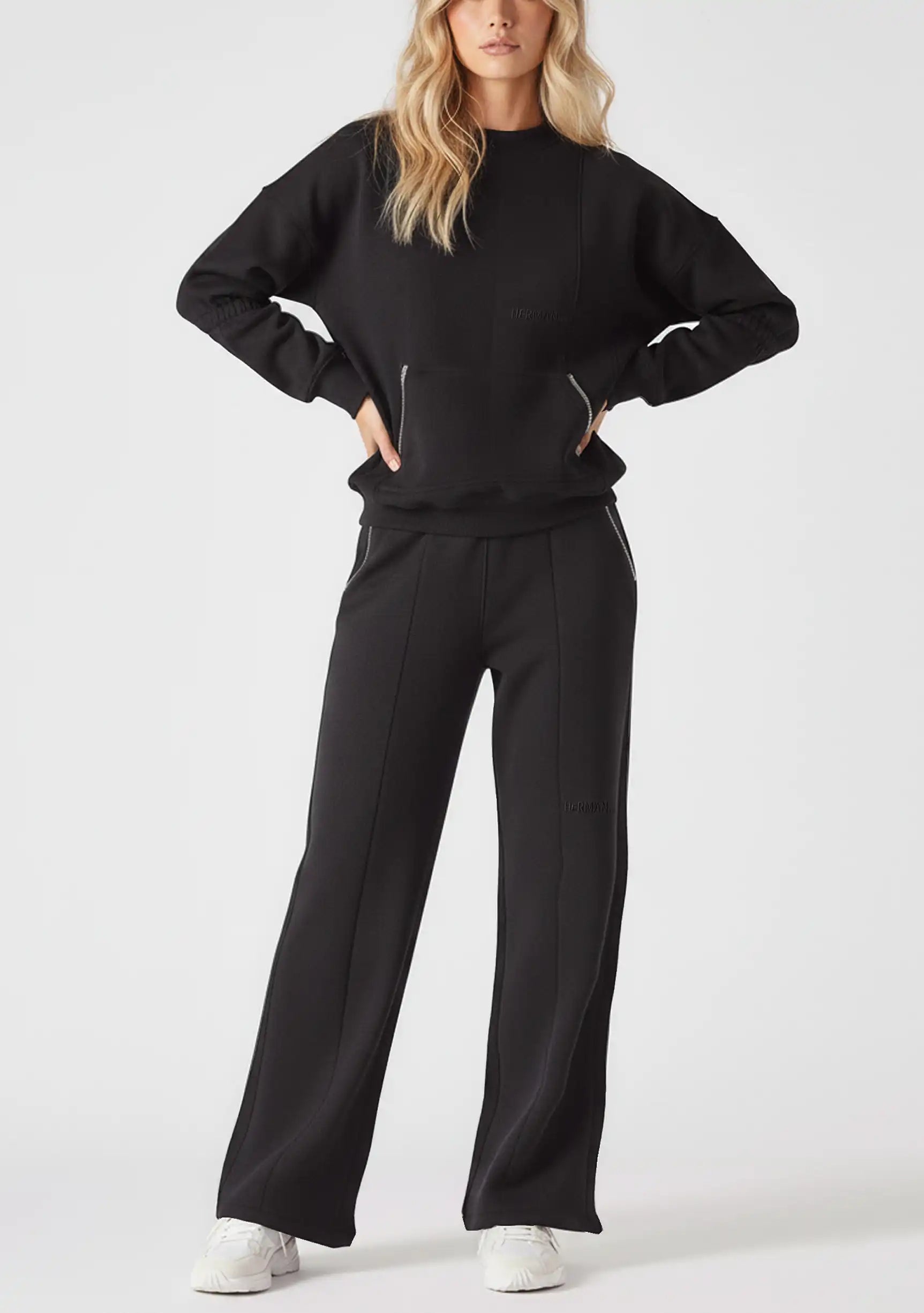 Model styled in a full loungewear set featuring the Herman black wide-leg joggers and a matching black sweatshirt