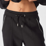 Close-up of the drawstring waistband and contrast blanket stitch detail on the front pockets of the Herman black joggers.