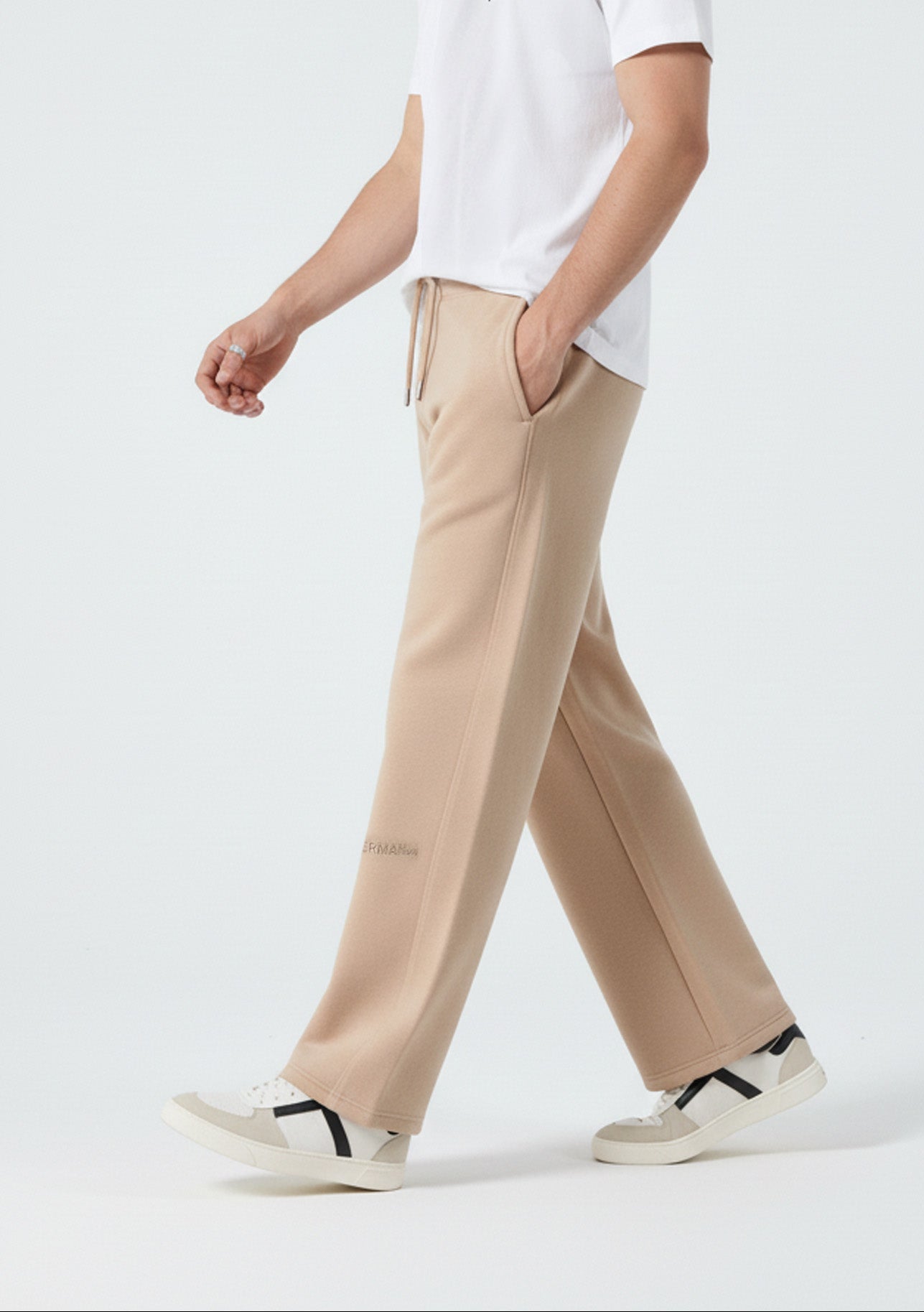 Side profile of a model walking in the Herman men's beige wide-leg joggers.