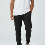 Full look of a model wearing the Herman men's black tapered joggers with a white t-shirt.