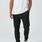 Full look of a model wearing the Herman men's black tapered joggers with a white t-shirt.