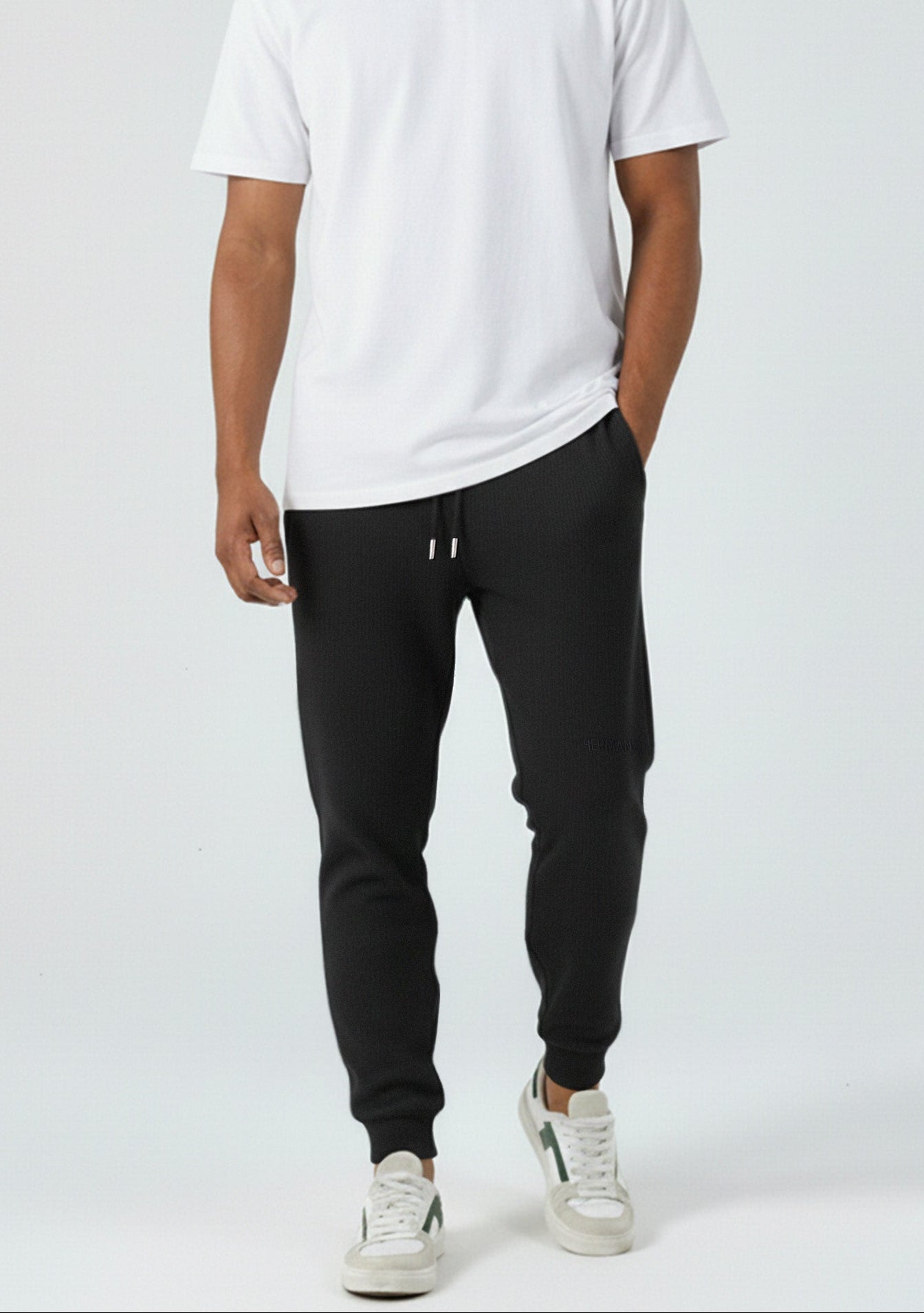 Full look of a model wearing the Herman men's black tapered joggers with a white t-shirt.