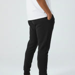 Side profile of a model wearing the Herman men's black tapered joggers.
