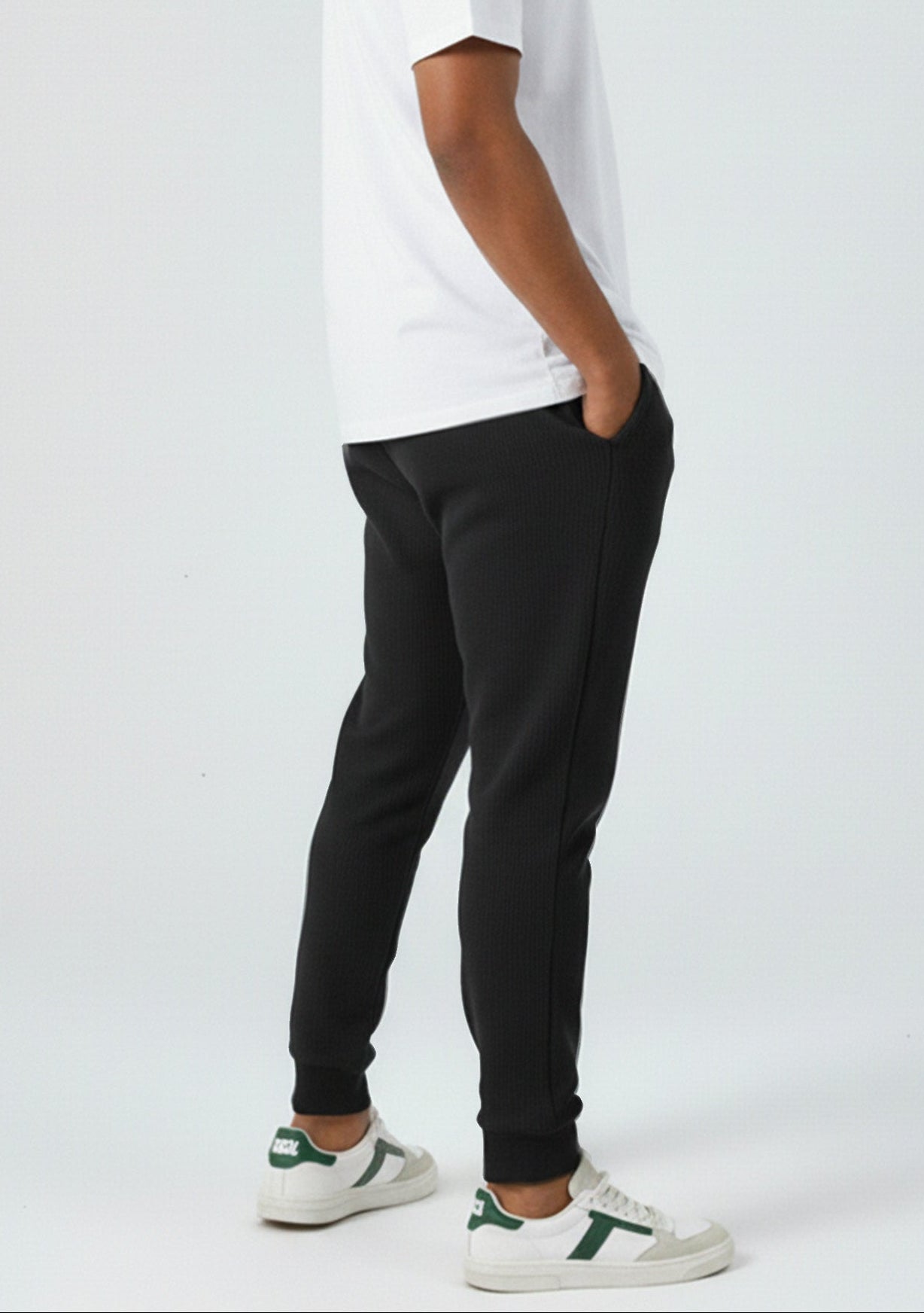 Side profile of a model wearing the Herman men's black tapered joggers.